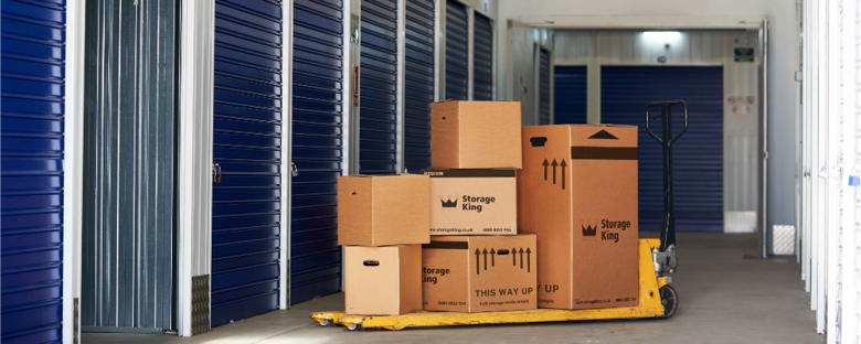 Storage boxes stacked on a moving trolley outside a Storage King storage unit