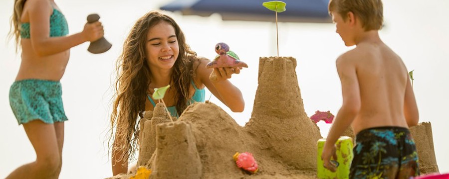 family makes a sandcastle at a beach