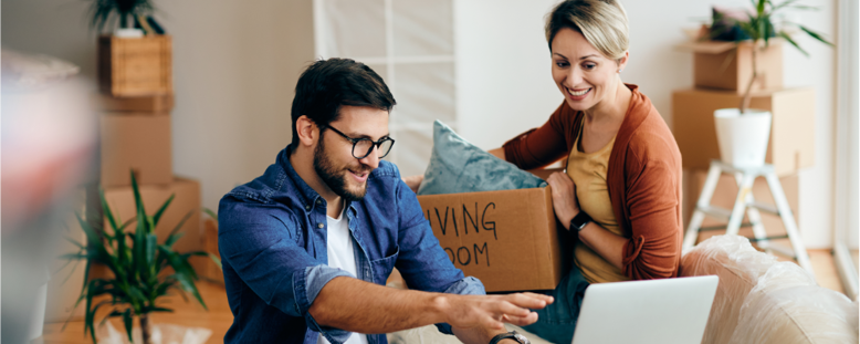 A couple looking at self storage options in West Bromwich on their laptop while packing up boxes in the living room
