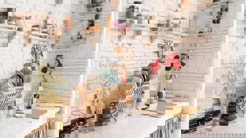 A kitchen with wooden shelving and a dry rack full of dishes.