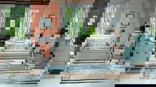 a living room with curved furniture and two blue rugs on the floor.