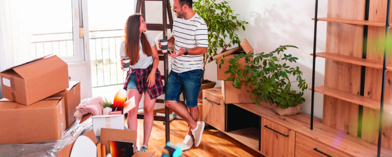 A couple in a half packed living room, considering using self storage.