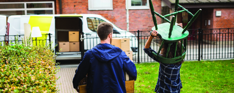 A couple moving furniture out of their home into a removals van