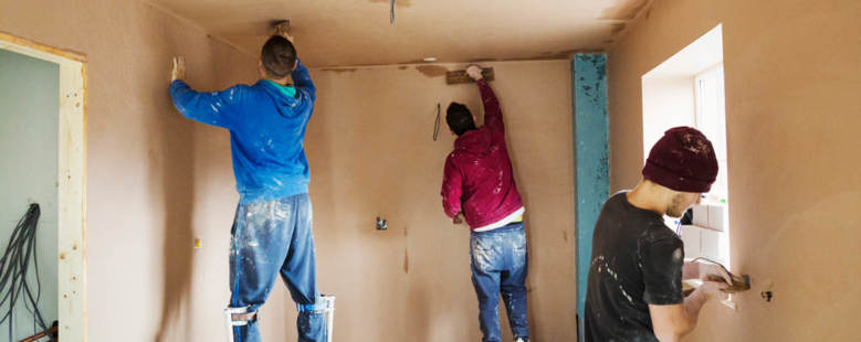 Three contractors renovating a room by painting the walls