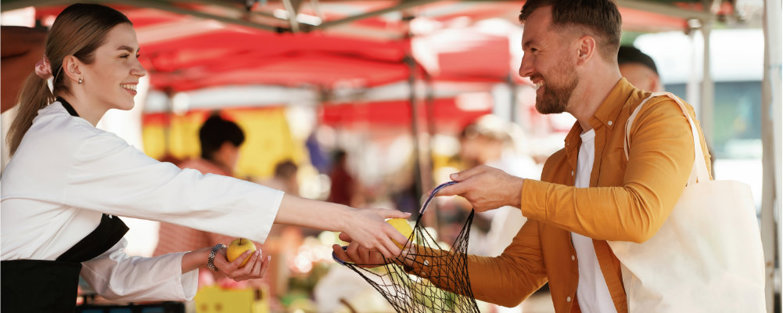 A maerket vendor selling fruit to a customer at the Frome Independant Market