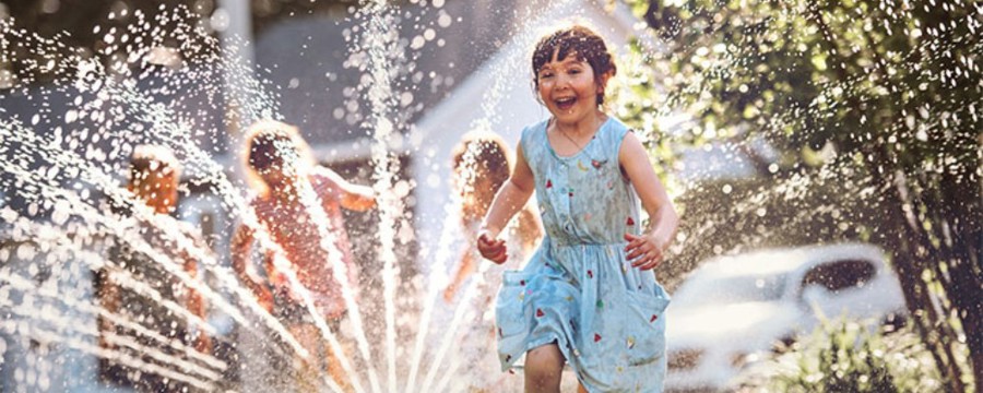 kids play in a sprinkler outside