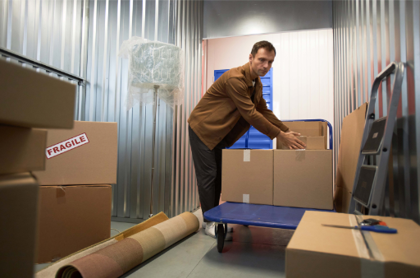 A Storage King customer packing moving boxes into their storage unit, using an on-site trolley